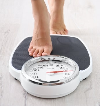 woman measuring her weight using scales on floor